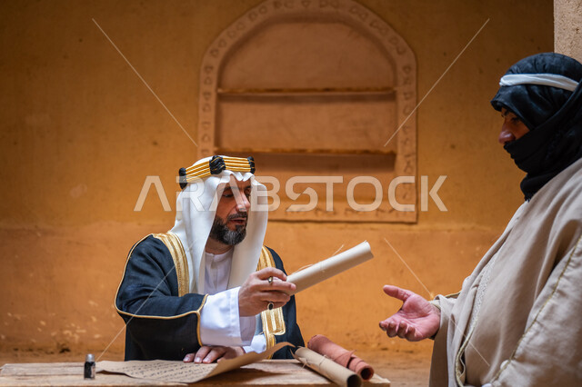 الفخر بأصالة المملكة، صورة مقربة لرجل عربي خليجي سعودي يرتدي الغترة والعقال الذهبي والبشت يقوم بتسليم مخطوطة جلد تاريخية إلى شخص آخر، يوم بدينا 22 فبراير, ارتداء الزي الشعبي في المناسبة الوطنية، الخطابات والمراسلات التراثية لتأسيس الدولة السعودية الأولى 1727م
