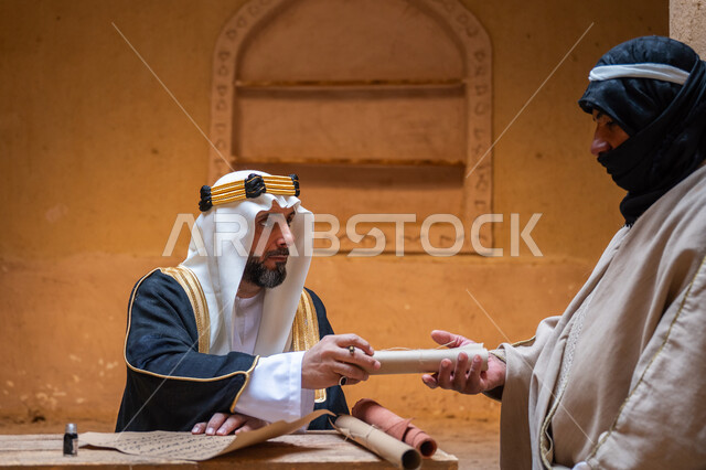 ارتداء الزي الشعبي في المناسبة الوطنية، الفخر بأصالة المملكة، صورة مقربة لرجل عربي خليجي سعودي يرتدي الغترة والعقال الذهبي والبشت يقوم بتسليم مخطوطة جلد تاريخية إلى شخص آخر، يوم بدينا 22 فبراير, الخطابات والمراسلات التراثية لتأسيس الدولة السعودية الأولى 1727م