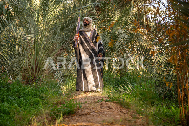 اصطياد الحيوانات البرية في المزرعة, ذكرى يوم التأسيس السعودي 1727 م, يوم بدينا 22 فبراير, حمل السلاح للدفاع عن الوطن, رجل عربي خليجي سعودي يرتدي الزي التقليدي يحمل بيده بندقية ويسير بين أشجار النخيل, توارث مهنة الصيد, حرفة شعبية تراثية