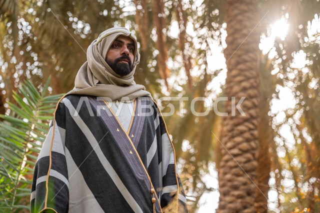 محمية طبيعية لزراعة أشجار النخيل, مهنة تقليدية شعبية, موسم حصاد وجني التمور, ذكرى يوم تأسيس الدولة السعودية الأولى في 1727م, يوم بدينا 22 فبراير, رجل عربي خليجي سعودي يرتدي الثوب التقليدي يقف في مزرعة النخل بالمملكة