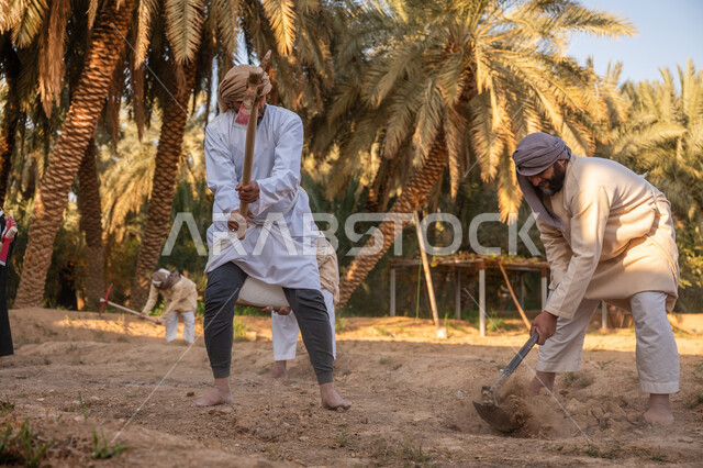 حرفة شعبية تراثية, مزرعة أشجار النخيل في المملكة, زراعة وتشجير الأراضي السعودية, إحياء ذكرى تأسيس الدولة السعودية الأولى 1727 م, يوم بدينا 22 فبراير, فلاحان عربيان خليجيان سعوديان يرتديان الزي التقليدي يقومان بحراثة الأرض, توارث مهنة الفلاحة