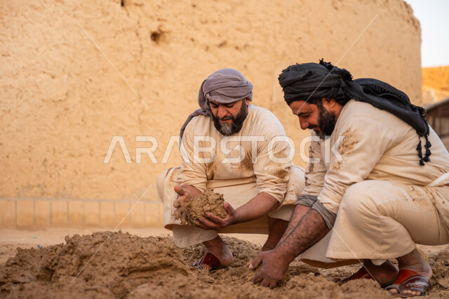 إحياء ذكرى يوم التأسيس1727 م, بناء الدولة السعودية الأولى، يوم بدينا 22 فبراير, عاملان عربيان يقومان بعجن الطين بأيديهم, الفخر والاعتزاز بالتراث السعودي العريق, تشييد وبناء البيوت الطينية التراثية التاريخية