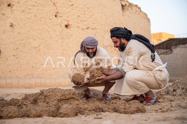 تشييد وبناء البيوت الطينية التراثية التاريخية, إحياء ذكرى يوم التأسيس1727 م, بناء الدولة السعودية الأولى، يوم بدينا 22 فبراير, عاملان عربيان يقومان بعجن الطين بأيديهم, الفخر والاعتزاز بالتراث السعودي العريق