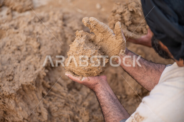 يوم بدينا 22 فبراير, صورة مقربة من الخلف لعامل عربي يقوم بعجن الطين بيديه, الفخر والاعتزاز بالتراث السعودي العريق, تشييد وبناء البيوت الطينية التراثية التاريخية, إحياء ذكرى يوم التأسيس1727 م, بناء الدولة السعودية الأولى