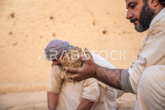 بناء الدولة السعودية الأولى، يوم بدينا 22 فبراير, عاملان عربيان يقومان بعجن الطين بأيديهم, الفخر والاعتزاز بالتراث السعودي العريق, تشييد وبناء البيوت الطينية التراثية التاريخية, إحياء ذكرى يوم التأسيس1727 م