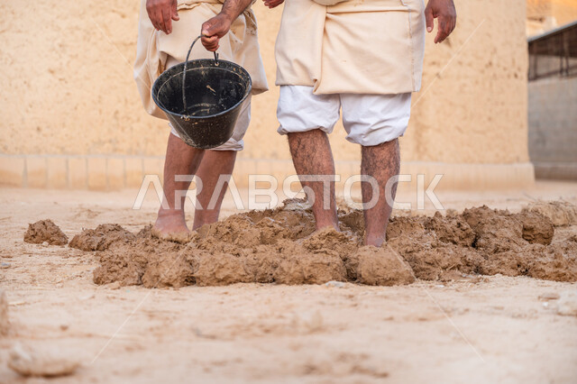 تشييد وبناء البيوت الطينية التراثية التاريخية, إحياء ذكرى يوم التأسيس1727 م, بناء الدولة السعودية الأولى، يوم بدينا 22 فبراير, عاملان عربيان يقومان بعجن الطين بأقدامهم, الفخر والاعتزاز بالتراث السعودي العريق