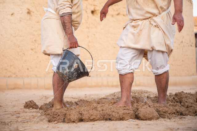 الفخر والاعتزاز بالتراث السعودي العريق, تشييد وبناء البيوت الطينية التراثية التاريخية, إحياء ذكرى يوم التأسيس1727 م, بناء الدولة السعودية الأولى، يوم بدينا 22 فبراير, عاملان عربيان يقومان بعجن الطين بأقدامهم
