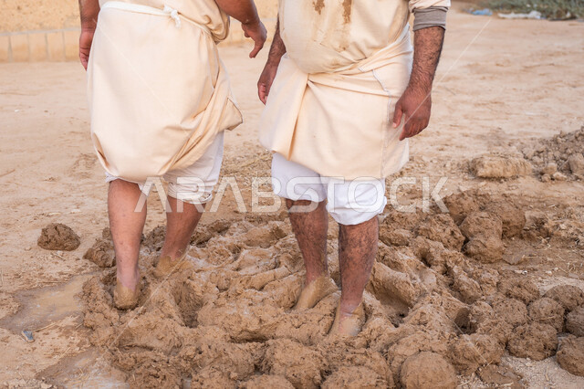 يوم بدينا 22 فبراير, الفخر والاعتزاز بالتراث السعودي العريق, تشييد وبناء البيوت الطينية التراثية التاريخية, إحياء ذكرى يوم التأسيس1727 م, بناء الدولة السعودية الأولى, عاملان عربيان يقومان بعجن الطين بأقدامهم