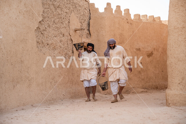 بناء الدولة السعودية الأولى, إحياء ذكرى يوم التأسيس1727 م, عاملان عربيان يقومان بنقل الطين ومواد البناء, يوم بدينا 22 فبراير, الفخر والاعتزاز بالتراث السعودي العريق, تشييد وبناء البيوت الطينية التراثية التاريخية