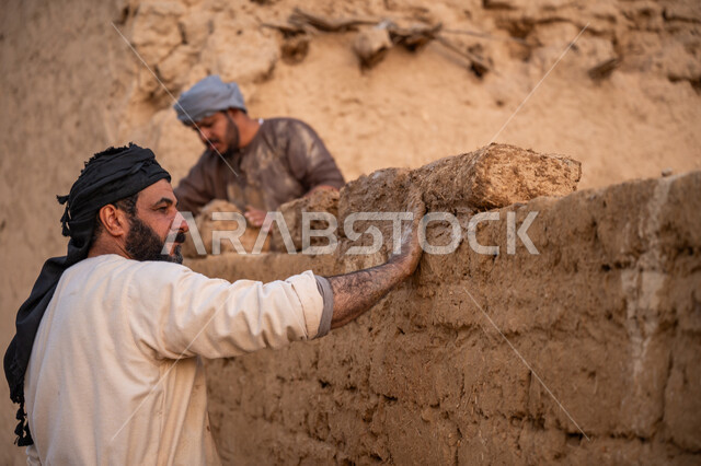 إحياء ذكرى يوم التأسيس1727 م, بناء الدولة السعودية الأولى, يوم بدينا 22 فبراير, الفخر والاعتزاز بالتراث السعودي العريق, عاملان عربيان يقومان ببناء بيت طيني شعبي, تشييد وبناء البيوت الطينية التراثية التاريخية