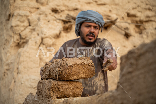 بناء الدولة السعودية الأولى, يوم بدينا 22 فبراير, الفخر والاعتزاز بالتراث السعودي العريق, عامل عربي يقوم ببناء بيت طيني شعبي, تشييد وبناء البيوت الطينية التراثية التاريخية, إحياء ذكرى يوم التأسيس1727 م