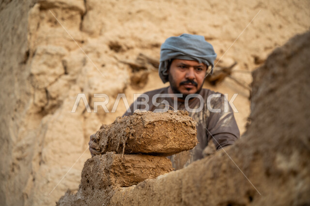 إحياء ذكرى يوم التأسيس1727 م, بناء الدولة السعودية الأولى, يوم بدينا 22 فبراير, الفخر والاعتزاز بالتراث السعودي العريق, عامل عربي يقوم ببناء بيت طيني شعبي, تشييد وبناء البيوت الطينية التراثية التاريخية