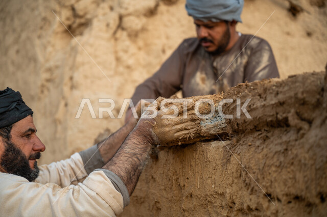 إحياء ذكرى يوم التأسيس1727 م, بناء الدولة السعودية الأولى, يوم بدينا 22 فبراير, الفخر والاعتزاز بالتراث السعودي العريق, عاملان عربيان يقومان ببناء بيت طيني شعبي, تشييد وبناء البيوت الطينية التراثية التاريخية