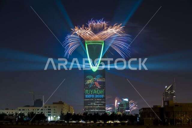 اطلاق الألعاب النارية امام برج المملكة المضيئ باللون الاخضر في وقت الليل أثناء الاحتفال في مناسبة الفوز في معرض اكسبو 2030 في السعودية، التطور و النمو الاقتصادي, عروض ثقافية و أنشطه ترفيهية، الفن الهندسي المعماري على الطراز الحديث