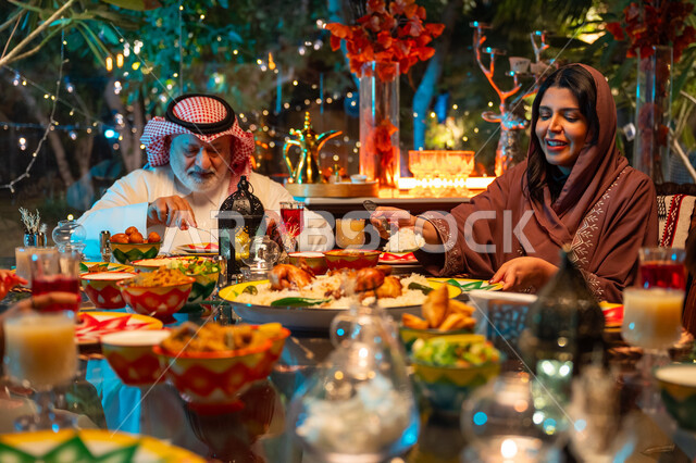 زينة المناسبات الإسلامية، تبادل الأحاديث بين أفراد الأسرة، أداء فريضة الصيام في شهر رمضان المبارك، سفرة مليئة بأصناف من المأكولات الشرقية الشهية، أجواء عائلية دينية رمضانية سعيدة، عائلة عربية خليجية سعودية مجتمعة حول مائدة الطعام