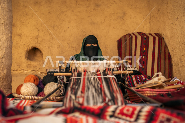 حرفة ومهنة يدوية قديمة، صناعة تقليدية تاريخية،  يوم بدينا ٢٢ فبراير، سيدة عربية خليجية سعودية ترتدي العباءة والبرقع تقوم بنسج وغزل الصوف، ذكرى تاسيس الدوله السعوديه الاولى ١٧٢٧م، منتج وطني محلي, إحياء التراث الشعبي السعودي