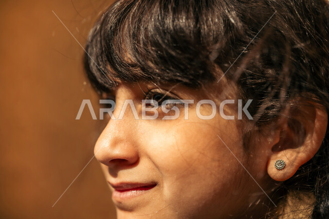 الأناقة والاهتمام بالمظهر الخارجي, مفهوم النعومة والبراءة, إحياء ذكرى يوم التأسيس السعودي 1727 م, يوم بدينا 22 فبراير, صورة مقربة لفتاة عربية خليجية سعودية ترتدي فتسان أزرق  تقف أمام بيت من الطين  وتنظر إلى مكان ما بإيماءات السعادة السرور