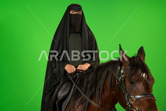 الفخر والاعتزاز بالهوية الوطنية، يوم بدينا 22 فبراير، توارث حب الجياد من الأجداد، اليوم الوطني السعودي 23 سبتمبر، بورتريه لامرأة عربية خليجية سعودية ترتدي البرقع والعباءة تمتطي فرس عربي, شغف تربية ورعاية الخيل، ذكرى تأسيس الدولة السعودية الأولى1727م, خلفية خضراء، كروما