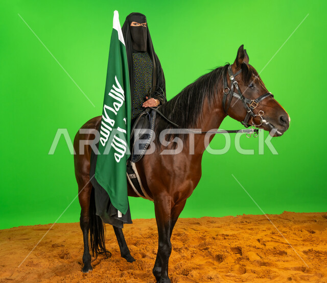 الفخر والاعتزاز بالهوية الوطنية، يوم بدينا 22 فبراير، اليوم الوطني السعودي 23 سبتمبر، بورتريه لامرأة عربية خليجية سعودية ترتدي البرقع والعباءة تمتطي فرس عربي تحمل علم التأسيس فوق الرمال الناعمة, شغف تربية ورعاية الخيل، ذكرى تأسيس الدولة السعودية الأولى1727م, خلفية خضراء، كروما