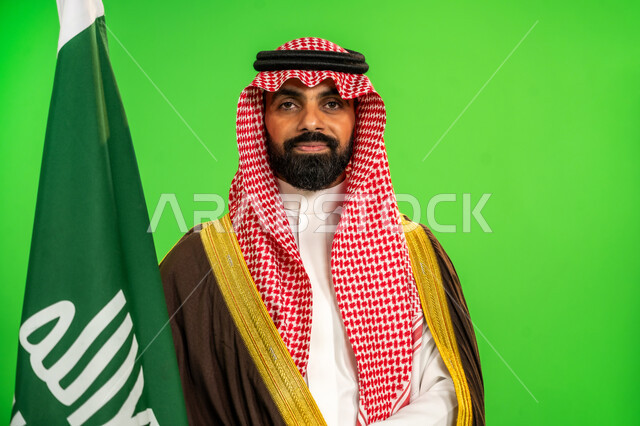 ارتداء الزي الشعبي في مناسبة وطنية, ذكرى تأسيس الدولة السعودية الأولى1727م, يوم بدينا22 فبراير, حب الوطن والانتماء اليه, بورتريه مقرب لرجل عربي خليجي سعودي يرتدي البشت والشماغ يمسك علم يوم التأسيس بتعابير الشموخ والفخر، خلفية خضراء، كروما