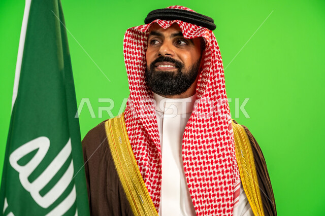 يوم بدينا22 فبراير, ذكرى تأسيس الدولة السعودية الأولى1727م, ارتداء الزي الشعبي في مناسبة وطنية, حب الوطن والانتماء اليه, بورتريه مقرب لرجل عربي خليجي سعودي يرتدي البشت والشماغ يمسك علم يوم التأسيس بتعابير الشموخ والفخر، خلفية خضراء، كروما