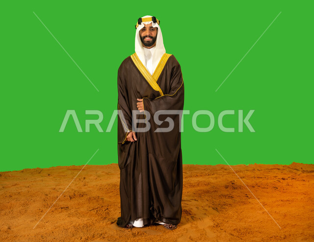 الفخر والاعتزاز بالهوية الوطنية، يوم بدينا22 فبراير، ذكرى تأسيس الدولة السعودية الأولى1727م, ارتداء الزي الشعبي في مناسبة وطنية, بورتريه لرجل عربي خليجي سعودي يرتدي البشت والعقال يقف باستقامة على الرمال الناعمة، الطول الكامل للجسم، خلفية خضراء، كروما