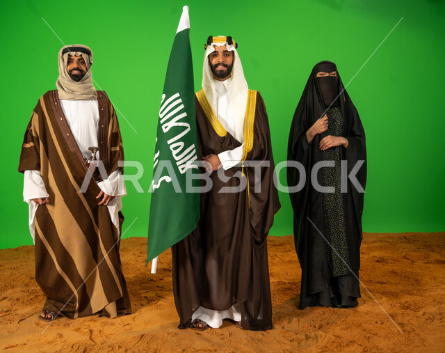 ذكرى تأسيس الدولة السعودية الأولى 1727م، العراقة والاصالة عند العرب، يوم بدينا 22 فبراير، بورتريه لأشخاص عرب خليجيين سعوديين يرتدون الزي الشعبي التقليدي في مناسبة وطنية يقفون على الرمال الناعمة، رجل سعودي يحمل علم يوم التأسيس، الطول الكامل للجسم، خلفية خضراء، كروما