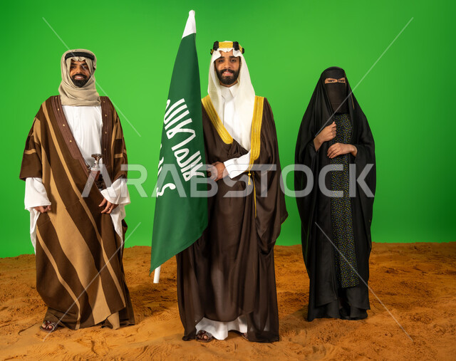 The nobility and authenticity of the Arabs, the day we started February 22, a portrait of Saudi Gulf Arabs wearing traditional dress on a national occasion standing on soft sand, a Saudi man holding the Founding Day flag, the anniversary of the founding of the first Saudi state 1727 AD, full body length, green background, chroma key