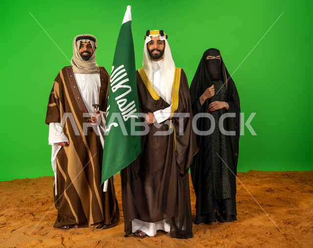 الاصالة والعراقة عند العرب، يوم بدينا 22 فبراير، بورتريه لأشخاص عرب خليجيين سعوديين يرتدون الزي الشعبي التقليدي في مناسبة وطنية يقفون على الرمال الناعمة، رجل سعودي يحمل علم يوم التأسيس، ذكرى تأسيس الدولة السعودية الأولى 1727م، الطول الكامل للجسم، خلفية خضراء، كروما