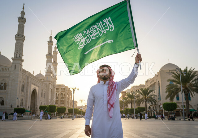مكان أداء فريضة الصلاة على وقتها، يوم العلم 11 مارس، اليوم الوطني السعودي 23 سبتمبر, رجل عربي خليجي سعودي يرتدي الثوب التقليدي والشماغ يحمل علم المملكة العربية السعودية ينظر إلى الكاميرا بإيماءات الفخر, الفن الهندسي المعماري لبناء المسجد على الطراز الإسلامي