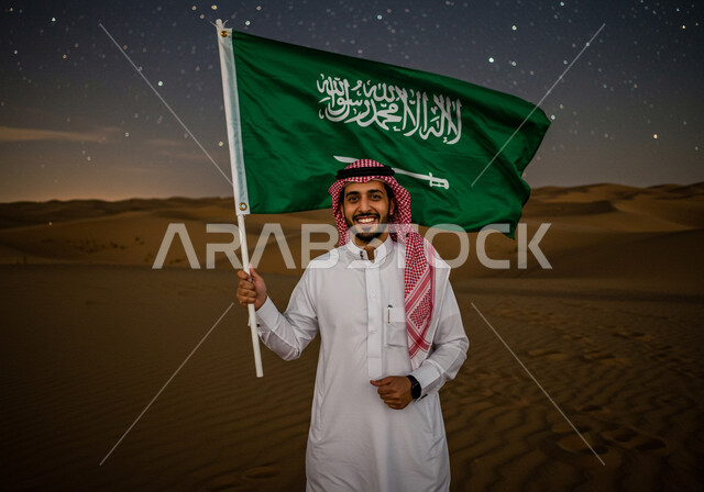 Sand formations in desert, Saudi National Day September 23, Desert environment at night, Flag Day March 11, Saudi Arabian Gulf man wearing traditional thobe and shemagh standing on soft sand in desert holding the Kingdom's flag looking at camera with proud gestures, starry sky background