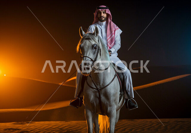 ارتباط تربية الخيول العربية بالأصالة والعراقة، رجل عربي خليجي سعودي يرتدي الثوب التقليدي والشماغ يمتطي الحصان بإيماءات السعادة والثقة بالنفس، ممارسة رياضة ركوب الخيل، تنمية مهارات الفروسية، الرمال الذهبية الناعمة في الصحراء وقت غروب الشمس