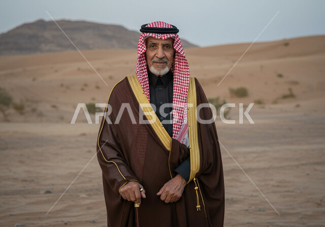 ارتداء الأزياء الشعبية في ذكرى تأسيس الدولة السعودية الاولى 22 فبراير, يوم بدينا 1727 م، الاعتزاز بالهوية الوطنية السعودية، شايب عربي خليجي سعودي يرتدي العقال والبشت التقليدي يقف على الرمال في الصحراء وينظر بإيماءات الفخر