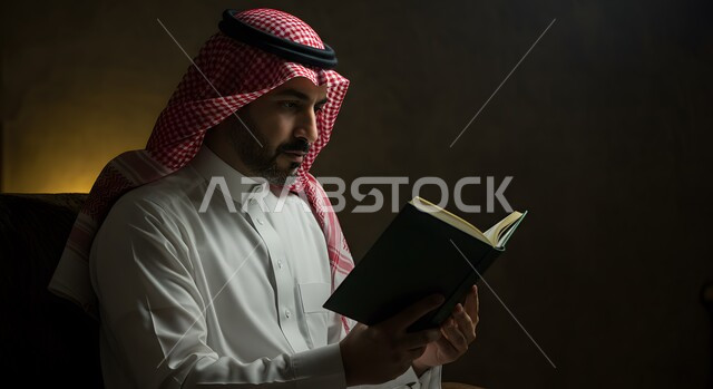 الاجتهاد في العبادة واداء الفريضة الدينية، قراءة و تلاوة القرآن الكريم، الإكثار من الطاعة وذكر الله تعالى، بورتريه مقرب لرجل عربي سعودي خليجي يرتدي الشماغ والثوب التقليدي يمسك بيده المصحف الشريف، التقرب الى رب العالمين في شهر رمضان المبارك، خلفية سوداء