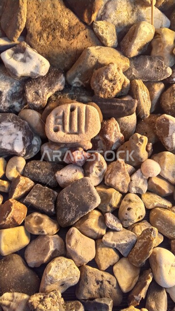 صورة مقربة لأحجار وحصوات على شاطئ البحر ، خلفية لصخور وحصوات شاطئ البحر الصغيرة ، حصى الشواطئ الطبيعية  ، صخور بحرية صغيرة ، حصى صغيرة من بين الحصوات على شاطئ البحر محفورة بإسم الله جل جلاله