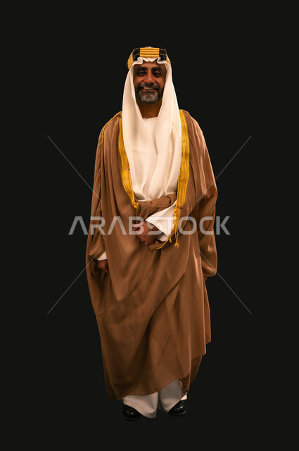 يوم بدينا 22 فبراير، الفخر بإنجازات المملكة، حب الوطن والانتماء إليه, بورتريه لرجل عربي خليجي سعودي يرتدي الغترة والعقال الذهبي والبشت ينظر إلى الكاميرا بإيماءات الشموخ، ذكرى تأسيس الدولة السعودية الأولى 1727م، الجسم بالطول الكامل، خلفية سوداء