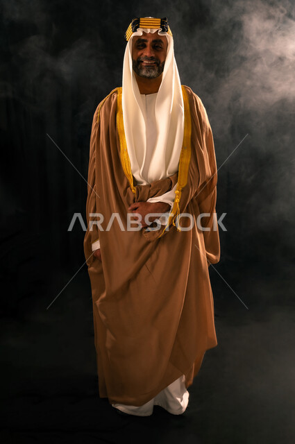 يوم بدينا 22 فبراير، الفخر بإنجازات المملكة، حب الوطن والانتماء إليه, بورتريه لرجل عربي خليجي سعودي يرتدي الغترة والعقال الذهبي والبشت ينظر إلى الكاميرا بإيماءات الشموخ، ذكرى تأسيس الدولة السعودية الأولى 1727م، الجسم بالطول الكامل، خلفية سوداء