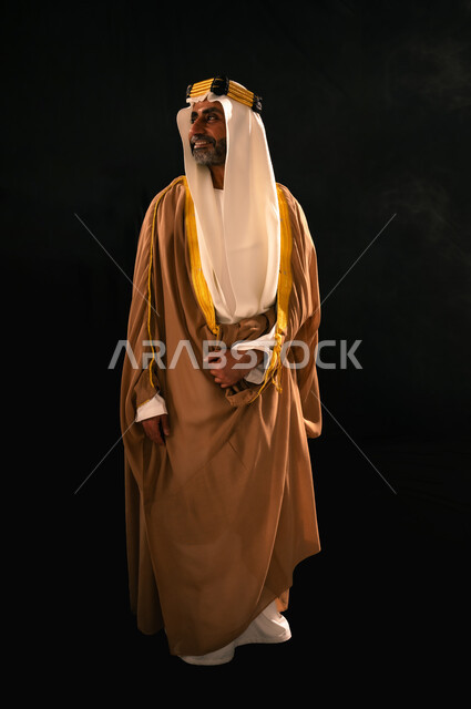 يوم بدينا 22 فبراير، الفخر بإنجازات المملكة، حب الوطن والانتماء إليه, بورتريه لرجل عربي خليجي سعودي يرتدي الغترة والعقال الذهبي والبشت ينظر إلى شيء ما بإيماءات الشموخ، ذكرى تأسيس الدولة السعودية الأولى 1727م، الجسم بالطول الكامل، خلفية سوداء