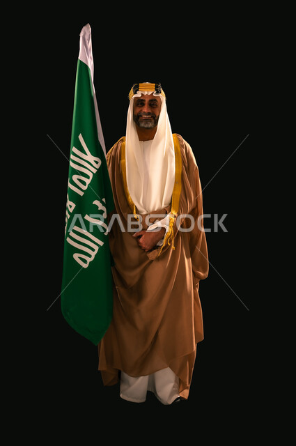يوم بدينا 22 فبراير، الفخر بإنجازات المملكة، إظهار الولاء والحب للوطن, بورتريه لرجل عربي خليجي سعودي يرتدي الغترة والعقال الذهبي والبشت يحمل علم التأسيس ينظر إلى الكاميرا بإيماءات الشموخ، ذكرى تأسيس الدولة السعودية الأولى 1727م، الجسم بالطول الكامل، خلفية سوداء