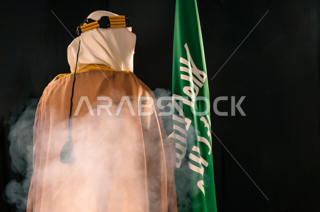 الفخر والاعتزاز بإنجازات المملكة، يوم بدينا 22 فبراير، إظهار الولاء والحب للوطن, بورتريه مقرب من الخلف لرجل عربي خليجي سعودي يرتدي الغترة والعقال الذهبي والبشت يحمل علم التأسيس، ذكرى تأسيس الدولة السعودية الأولى 1727م، خلفية سوداء