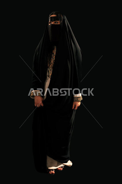يوم بدينا 22 فبراير، الفخر بإنجازات المملكة، بورتريه لامرأة عربية خليجية سعودية ترتدي البرقع والعباءة تنظر إلى شيء ما بإيماءات الشموخ، ذكرى تأسيس الدولة السعودية الأولى 1727م، حب الوطن والانتماء إليه, الجسم بالطول الكامل، خلفية سوداء