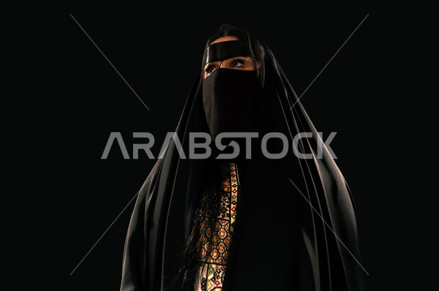 ذكرى تأسيس الدولة السعودية الأولى 1727م، حب الوطن والانتماء إليه, الفخر بإنجازات المملكة، بورتريه مقرب لامرأة عربية خليجية سعودية ترتدي البرقع والعباءة تنظر إلى شيء ما بإيماءات الشموخ، يوم بدينا 22 فبراير، خلفية سوداء