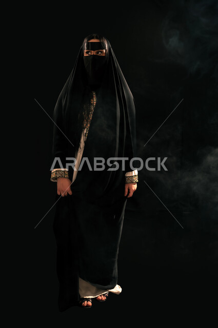 يوم بدينا 22 فبراير، الفخر بإنجازات المملكة، بورتريه لامرأة عربية خليجية سعودية ترتدي البرقع والعباءة تنظر إلى شيء ما بإيماءات الشموخ، ذكرى تأسيس الدولة السعودية الأولى 1727م، حب الوطن والانتماء إليه, الجسم بالطول الكامل، خلفية سوداء