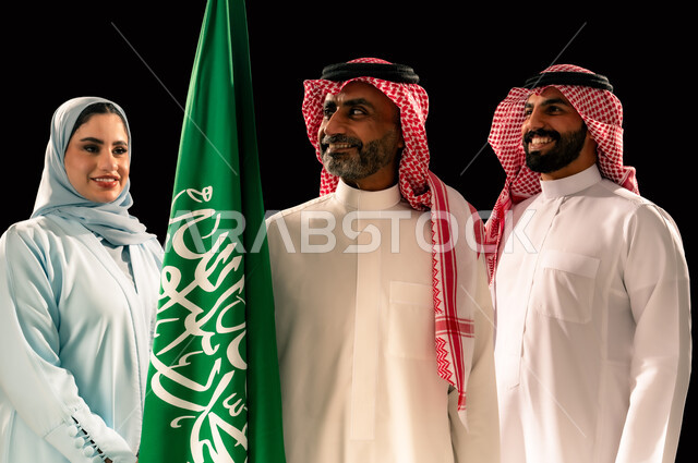 ترسيخ جذور الانتماء الوطني, إحياء ذكرى اليوم الوطني السعودي 23 سبتمبر, يوم العلم 11 مارس, اظهار الحب و التفاني للبلاد, النظر الى العلم بإيماءات السرور و الفخر, بورتريه مقرب لعائلة عربية خليجية سعودية مبتسمة تقف بجانب علم المملكة, خلفية سوداء