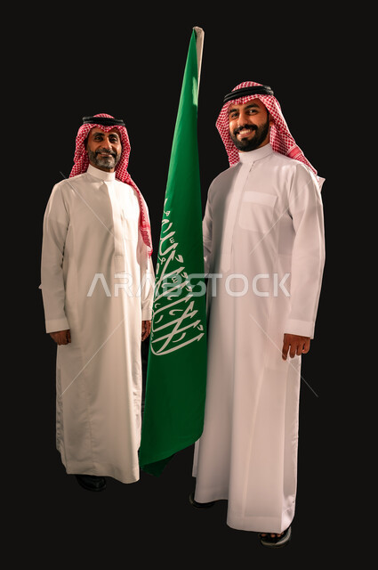 يوم العلم 11 مارس, النظر الى الكاميرا بإيماءات الفخر و السرور بالانتماء للوطن, إحياء ذكرى اليوم الوطني السعودي 23 سبتمبر, بورتريه لرجلان عربيان خليجيان سعوديان مبتسمان يرتديان الشماغ و الثوب التقليدي يقفان بجانب علم المملكة, الجسم بالطول الكامل, خلفية سوداء