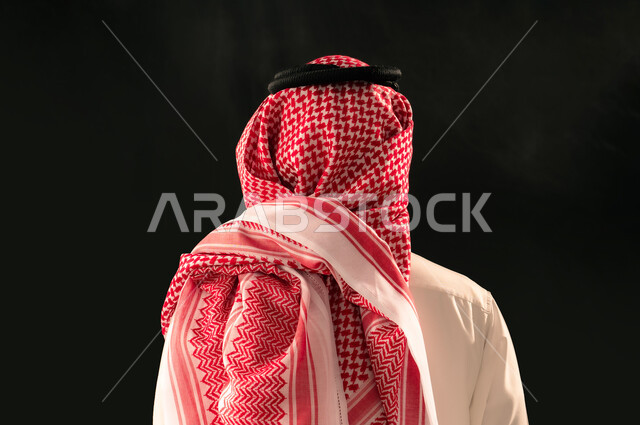 الاهتمام بالمظهر الخارجي، بورتريه مقرب من الخلف لرجل عربي خليجي سعودي يرتدي الثوب التقليدي والشماغ يقف باستقامة، مفهوم الرجولة والأناقة، خلفية سوداء