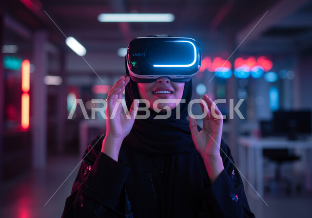 محاكاه العالم الخيالي، الاندماج والتفاعل مع العناصر الهولوجرامية، استخدام الأجهزة التقنية الحديثة والمتطورة، صورة مقربة لامرأة عربية خليجية سعودية محجبة ترتدي عباءة سوداء وتضع نظارة الواقع الافتراضي، مفهوم التطور التقني والتكنولوجي، ايماءات محاولة الامساك بشيء ما