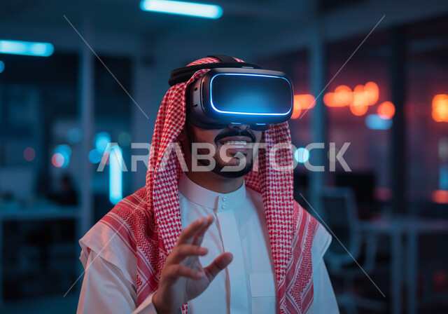 تعابير محاولة الامساك بشيء ما، الاندماج والتفاعل مع العناصر الهولوجرامية، مفهوم التطور التقني والتكنولوجي، استعمال الأجهزة التقنية الحديثة والمتطورة، محاكاه العالم الخيالي، صورة مقربة لرجل عربي خليجي سعودي يرتدي الشماغ والثوب التقليدي يضع نظارة الواقع الافتراضي