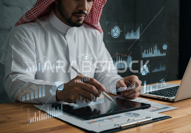 تطوير الشركة والمشاريع الاقتصادية، رسوم بيانية إحصائية للبورصة المالية، عناصر هولوجرامية ثلاثية الأبعاد، دمج التكنولوجيا المتطورة بالعمل، مفهوم التحول الرقمي، رجل عربي خليجي سعودي يرتدي الثوب التقليدي والشماغ يقوم بكتابة الارقام والاحصائيات على جهاز التابلت