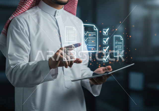 مفهوم إنجاز جميع المهام المطلوبة، دمج التكنولوجيا المتطورة بالعمل، صورة مقربة لرجل عربي خليجي سعودي يرتدي الثوب التقليدي والشماغ يحمل بيده جهاز التابليت تخظهر منه ايقونات مضيئة، عناصر ورموز هولوجرامية ثلاثية الأبعاد